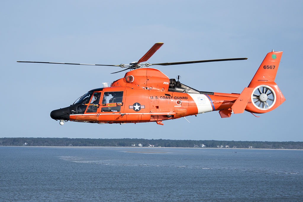 A Coast Guard Air Station Savannah MH-65 Dolphin helicopter flys over the Savannah River entrance March. 15, 2019, as the Cutter Eagle transits down the Savannah River towards Savannah, Georgia. Air Station Savannah welcomed the Eagle crew as they arrived in Savannah for St. Patrick’s Day weekend. (U.S. Coast Guard photo by Petty Officer 3rd Class Ryan Dickinson)